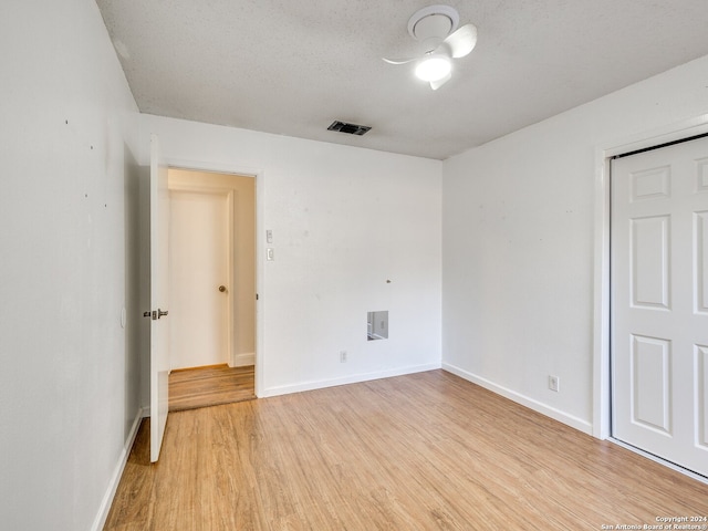 unfurnished room featuring light hardwood / wood-style flooring and a textured ceiling