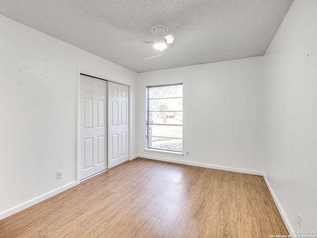 unfurnished bedroom featuring a closet, a textured ceiling, and light hardwood / wood-style flooring