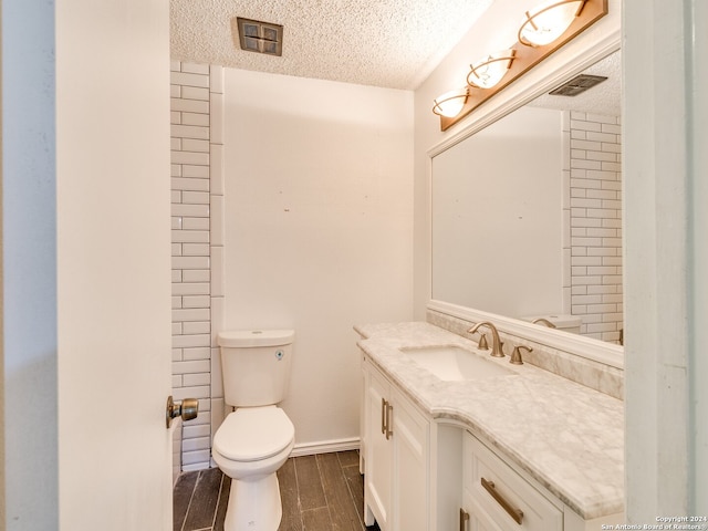 bathroom featuring hardwood / wood-style flooring, vanity, toilet, and a textured ceiling