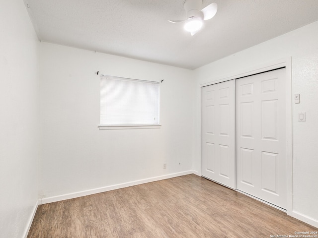 unfurnished bedroom with a closet, light hardwood / wood-style flooring, ceiling fan, and a textured ceiling