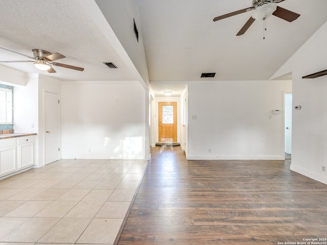 spare room with vaulted ceiling, ceiling fan, light hardwood / wood-style flooring, and a textured ceiling