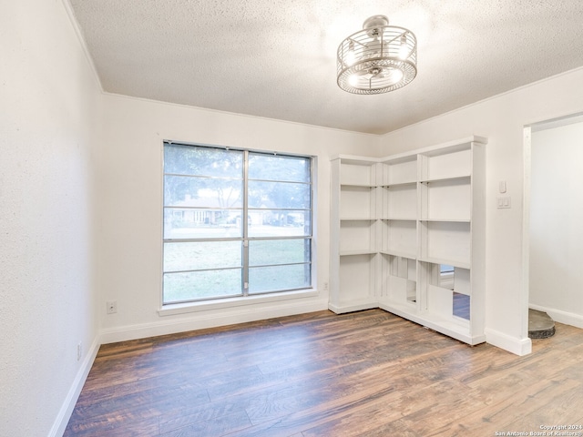 unfurnished room featuring wood-type flooring, a textured ceiling, and ornamental molding