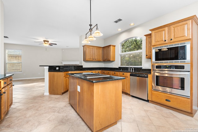 kitchen featuring a healthy amount of sunlight, light tile patterned floors, a kitchen island, and appliances with stainless steel finishes