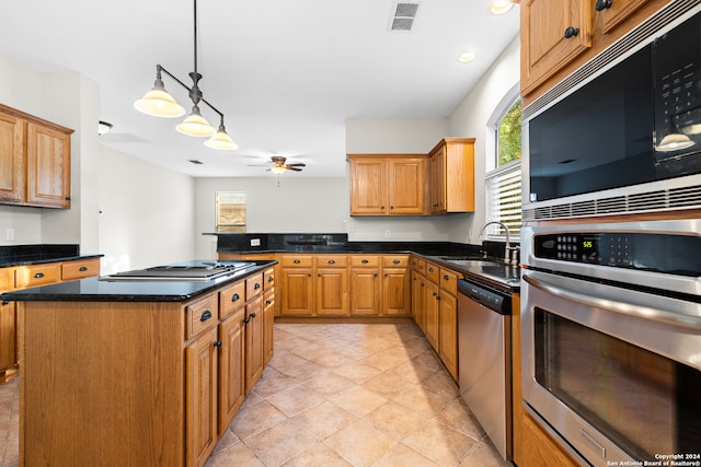 kitchen featuring stainless steel appliances, a kitchen island, pendant lighting, sink, and ceiling fan