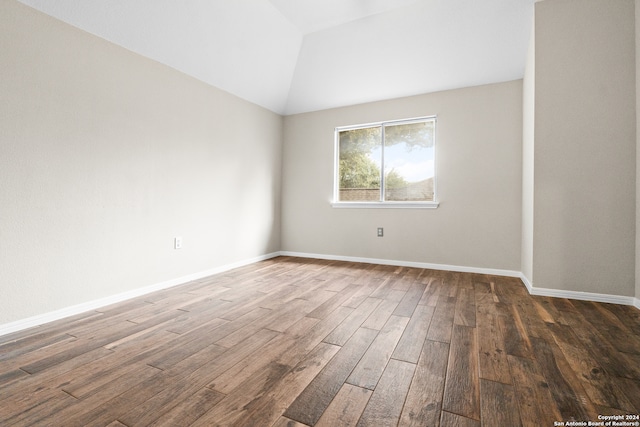 spare room featuring lofted ceiling and dark hardwood / wood-style floors