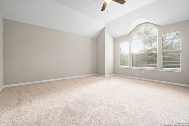 carpeted spare room featuring ceiling fan and vaulted ceiling