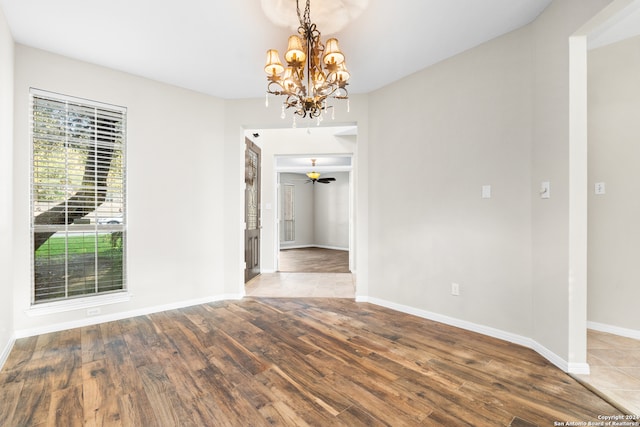 unfurnished dining area featuring ceiling fan with notable chandelier and hardwood / wood-style flooring