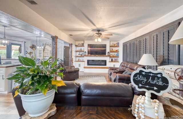 360 Benson Rd, Uvalde, TX 78801 - living area featuring ceiling fan, a chandelier, a textured ceiling, and a glass covered fireplace