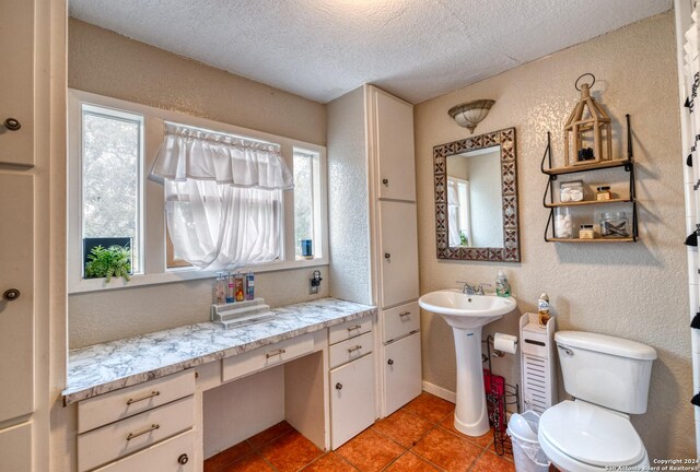 360 Benson Rd, Uvalde, TX 78801 - bathroom featuring a textured ceiling, tile patterned flooring, a textured wall, toilet, and a sink