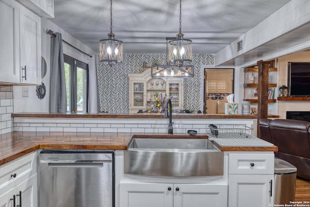 kitchen featuring dishwasher, sink, decorative light fixtures, and white cabinets