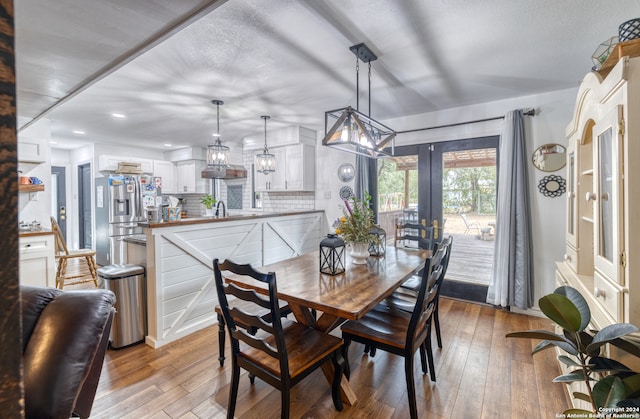 dining area with french doors, light wood-type flooring, and sink