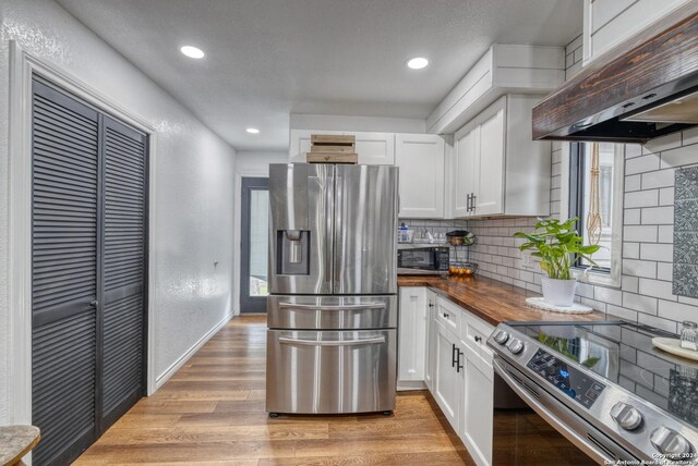 360 Benson Rd, Uvalde, TX 78801 - kitchen with stainless steel appliances, under cabinet range hood, decorative backsplash, white cabinets, and recessed lighting