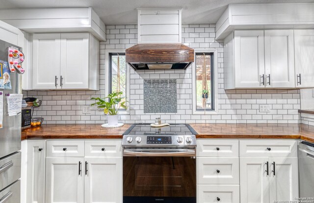 360 Benson Rd, Uvalde, TX 78801 - kitchen with butcher block counters, appliances with stainless steel finishes, premium range hood, decorative backsplash, and white cabinets