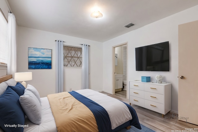 bedroom featuring connected bathroom, multiple windows, and light hardwood / wood-style floors