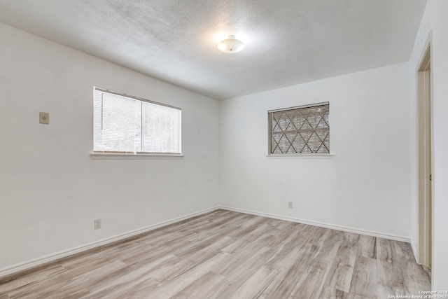 spare room featuring a textured ceiling and light hardwood / wood-style floors