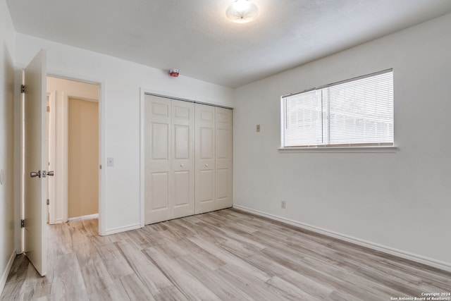 unfurnished bedroom with a closet and light hardwood / wood-style floors