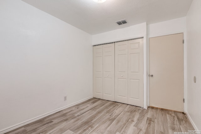 unfurnished bedroom with a closet and light wood-type flooring