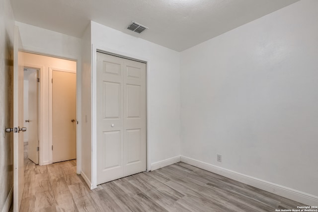 unfurnished bedroom featuring light wood-type flooring and a closet