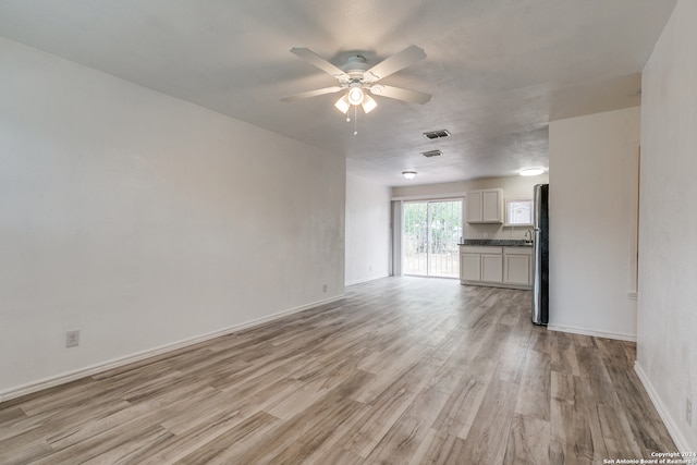 unfurnished living room featuring ceiling fan and light hardwood / wood-style floors