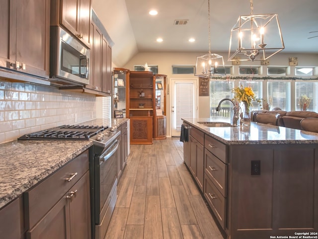 kitchen with stainless steel appliances, light hardwood / wood-style floors, sink, a kitchen island with sink, and pendant lighting