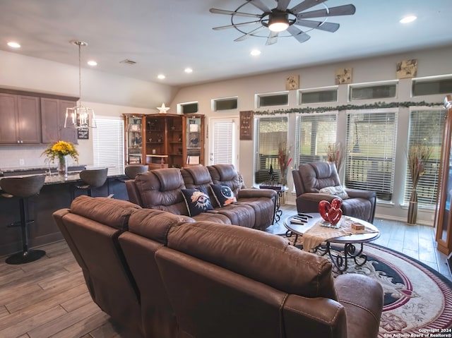 living room featuring light wood-type flooring and ceiling fan with notable chandelier