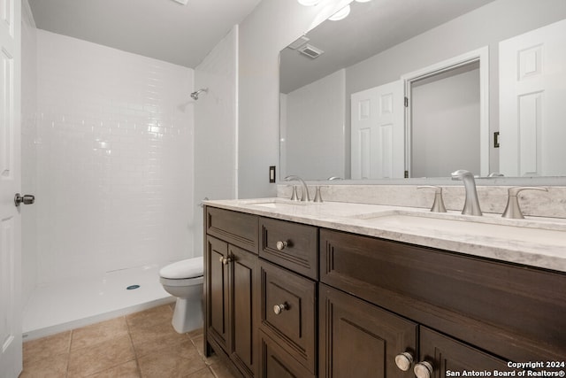 bathroom featuring vanity, tile patterned flooring, toilet, and a tile shower