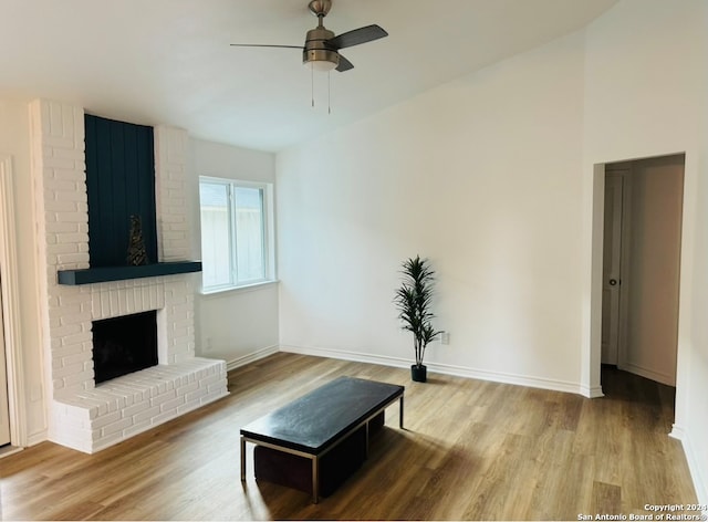 living room with a brick fireplace, light hardwood / wood-style floors, and ceiling fan