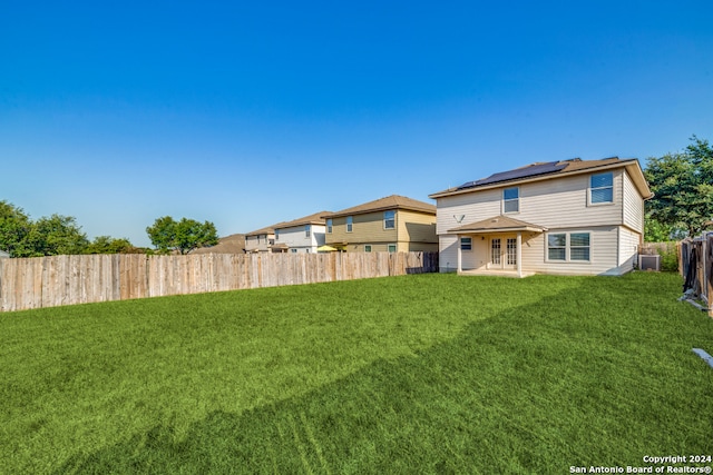 rear view of house featuring a lawn and central AC