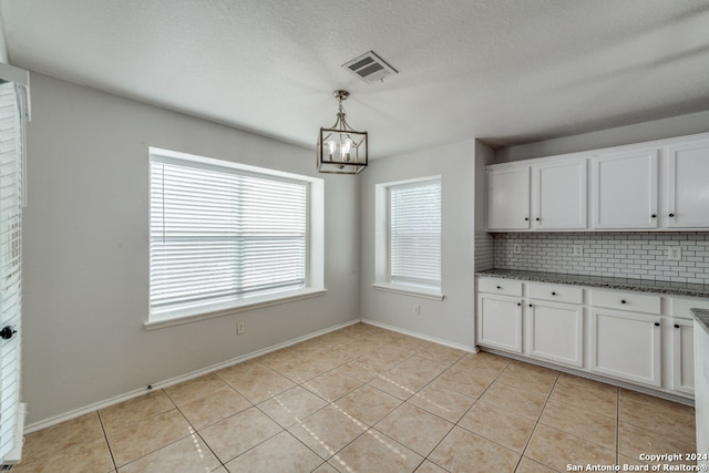 kitchen featuring white cabinetry, light tile patterned floors, decorative light fixtures, a notable chandelier, and decorative backsplash