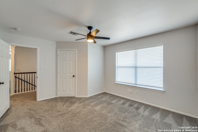 empty room featuring ceiling fan, a textured ceiling, and carpet flooring