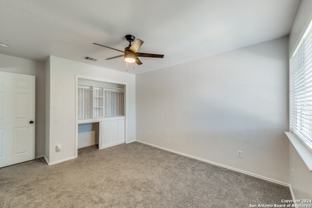 unfurnished bedroom with ceiling fan, multiple windows, and light colored carpet