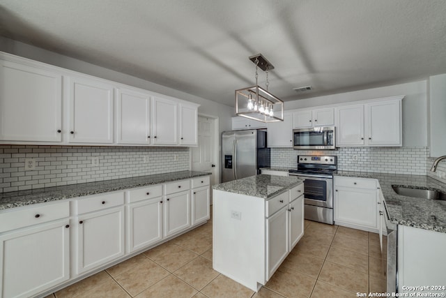 kitchen with white cabinets, appliances with stainless steel finishes, sink, and a kitchen island