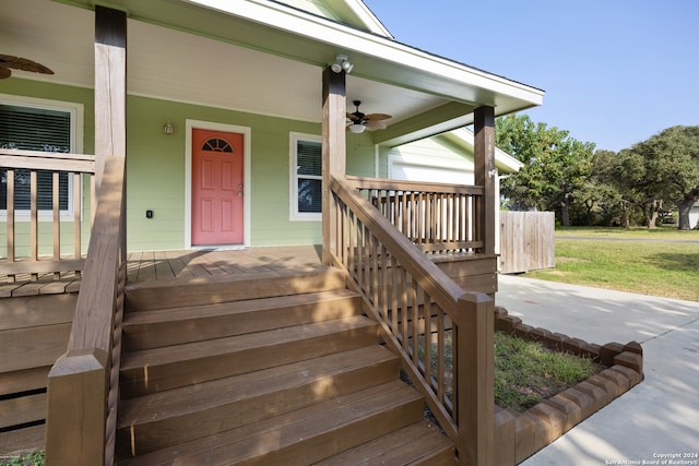 doorway to property featuring covered porch, ceiling fan, and a lawn