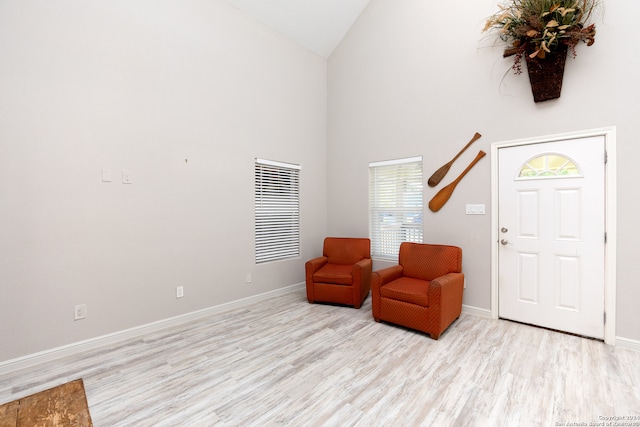 sitting room with high vaulted ceiling and light hardwood / wood-style flooring