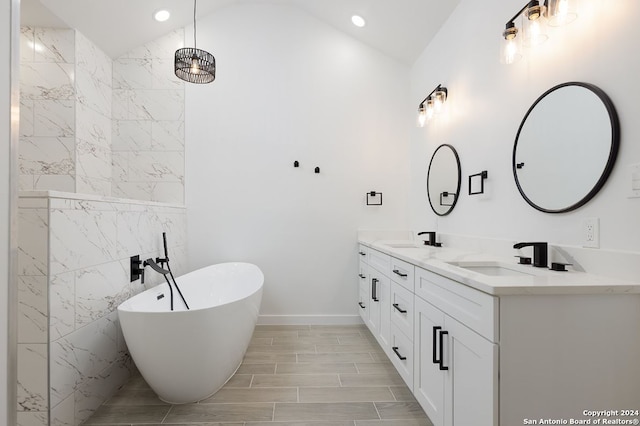 bathroom with vanity, a bathtub, and vaulted ceiling