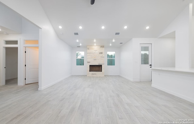 unfurnished living room featuring light wood-type flooring, a fireplace, and lofted ceiling