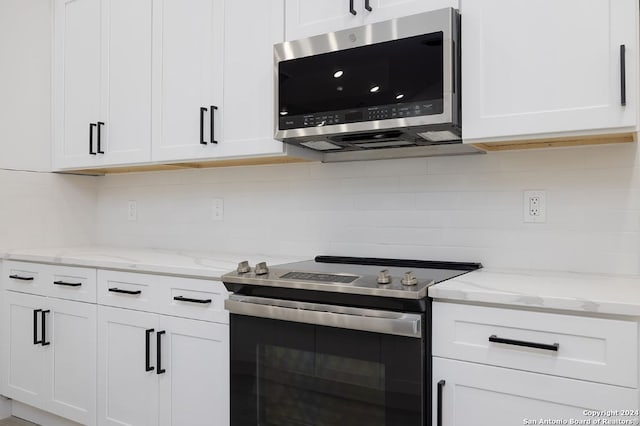 kitchen featuring stainless steel appliances, light stone countertops, white cabinets, and backsplash