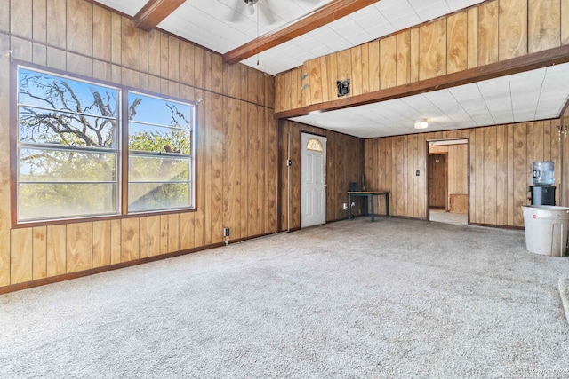 unfurnished living room with light colored carpet, wooden walls, and beam ceiling