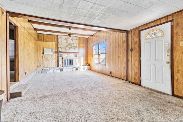 unfurnished living room with wood walls, a fireplace, beam ceiling, and carpet flooring