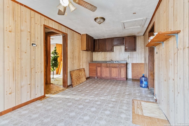 kitchen featuring ornamental molding, wooden walls, sink, and ceiling fan