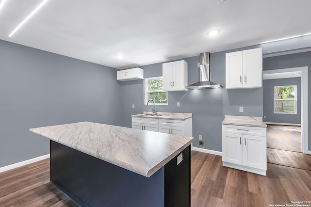 kitchen featuring wall chimney exhaust hood, white cabinetry, and a kitchen island