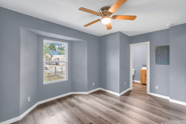 spare room with electric panel, ceiling fan, and light hardwood / wood-style floors