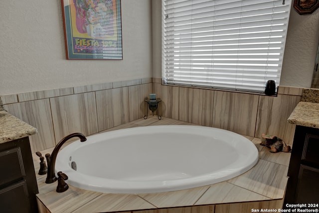 bathroom with vanity and tiled tub