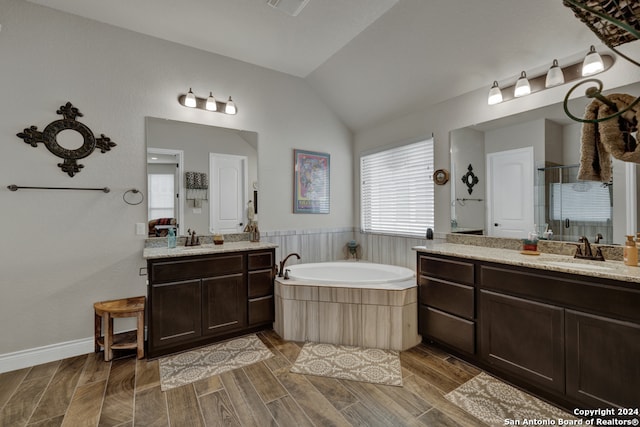 bathroom featuring vanity, independent shower and bath, lofted ceiling, and hardwood / wood-style flooring