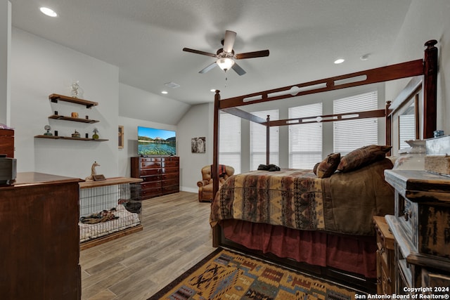 bedroom with light hardwood / wood-style floors, multiple windows, a textured ceiling, and lofted ceiling