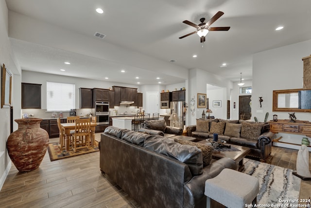 living room with light wood-type flooring and ceiling fan