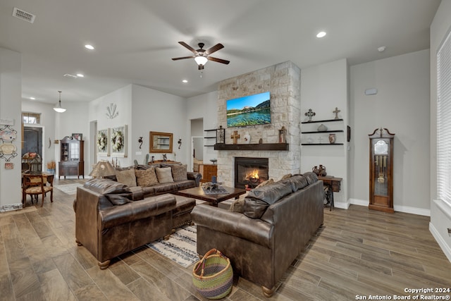 living room with ceiling fan, hardwood / wood-style flooring, and a stone fireplace