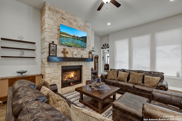 living room with a stone fireplace, hardwood / wood-style floors, and ceiling fan