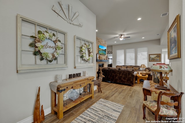 living room with a fireplace, ceiling fan, and light hardwood / wood-style flooring