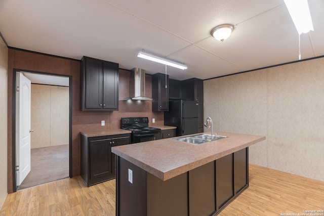 kitchen featuring a center island with sink, wall chimney exhaust hood, black appliances, sink, and light wood-type flooring